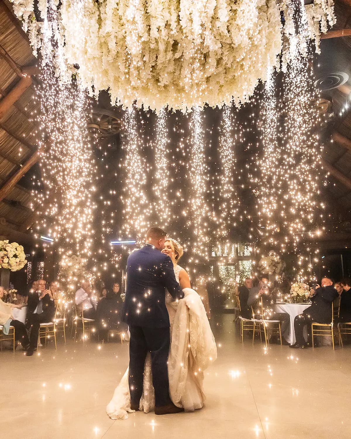 Bride and groom dancing beneath a sparkler chandelier at their reception