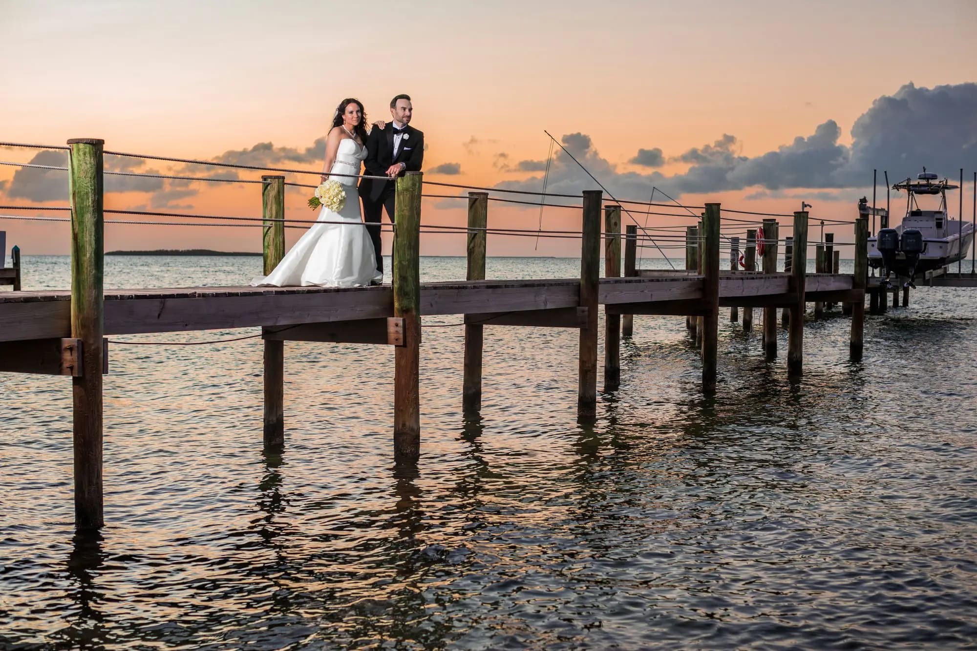 Couple posing on a pier at sunset — destination wedding photography by Boogietek Photo+Cinema